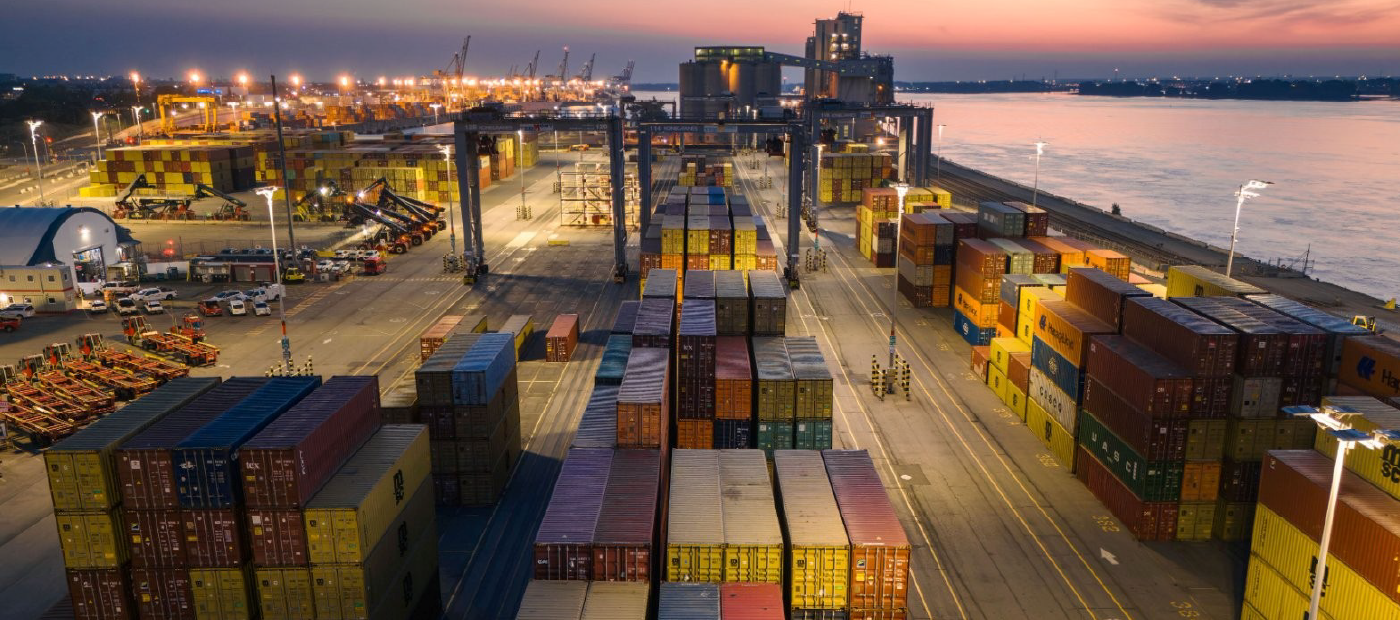 Several cargo containers and loading cranes on a port in the evening