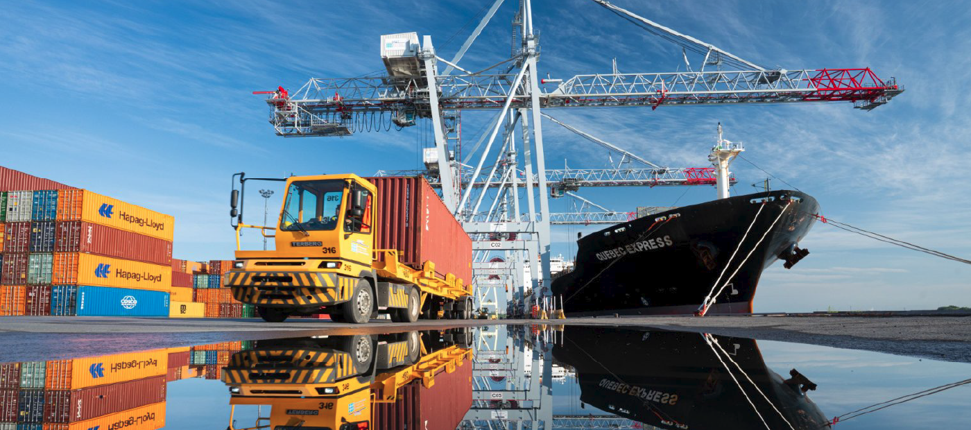 In order from left to right: cargo containers, a truck, a crane and a ship