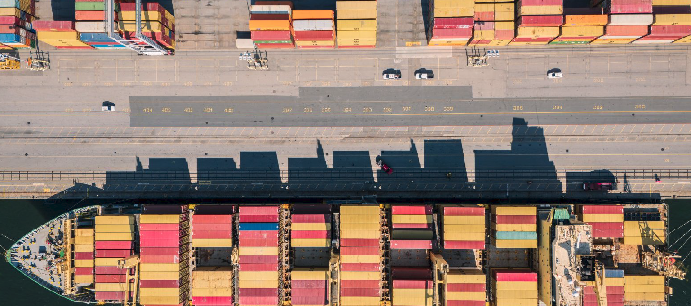 Arieal view of a shipping yard, with several cargo containers and a ship with cargo containers