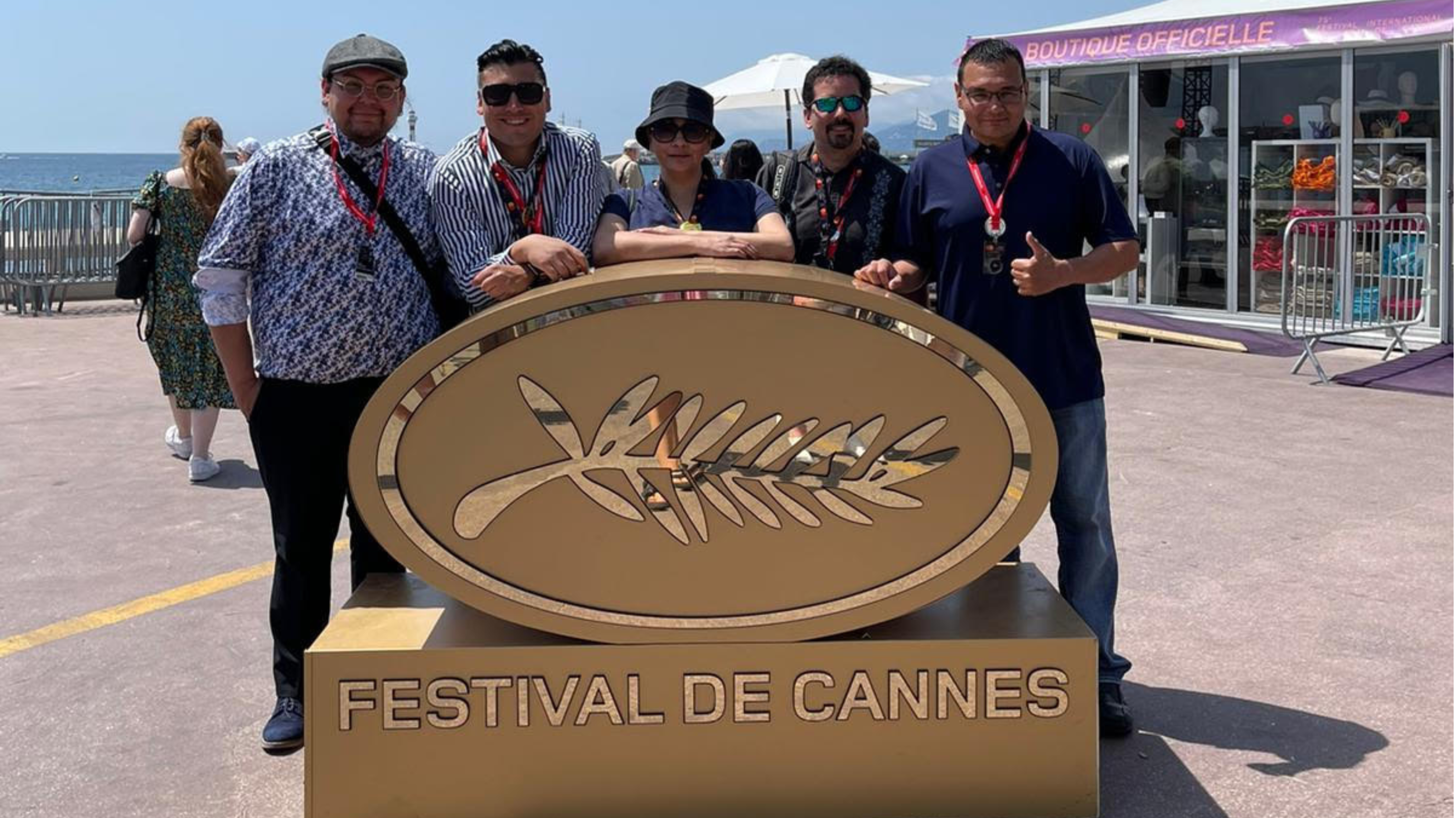 A group of representatives standing in front of a sign. Text reads: Festival De Cannes