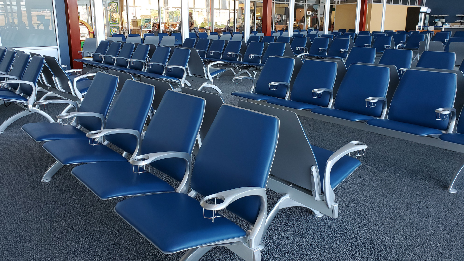 Image of Airport seating area filled with blue chairs.