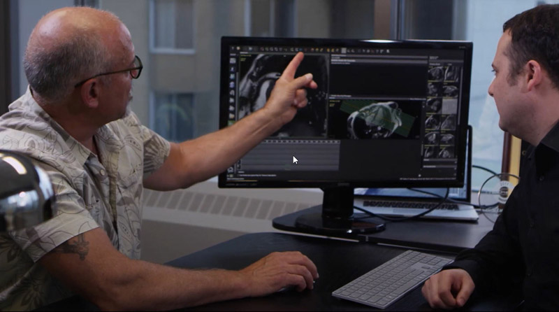 Two men view a digital scan of a heart on a monitor between them