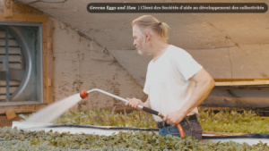 Un employé de Green Eggs and Ham arrose des semis dans une serre
