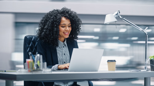 Une femme assise à un bureau utilise un ordinateur portable