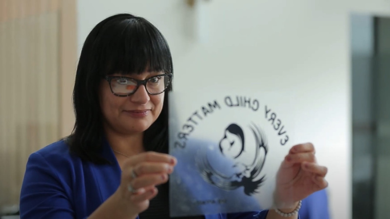 Woman holding a transparent sheet with a T-shirt design.