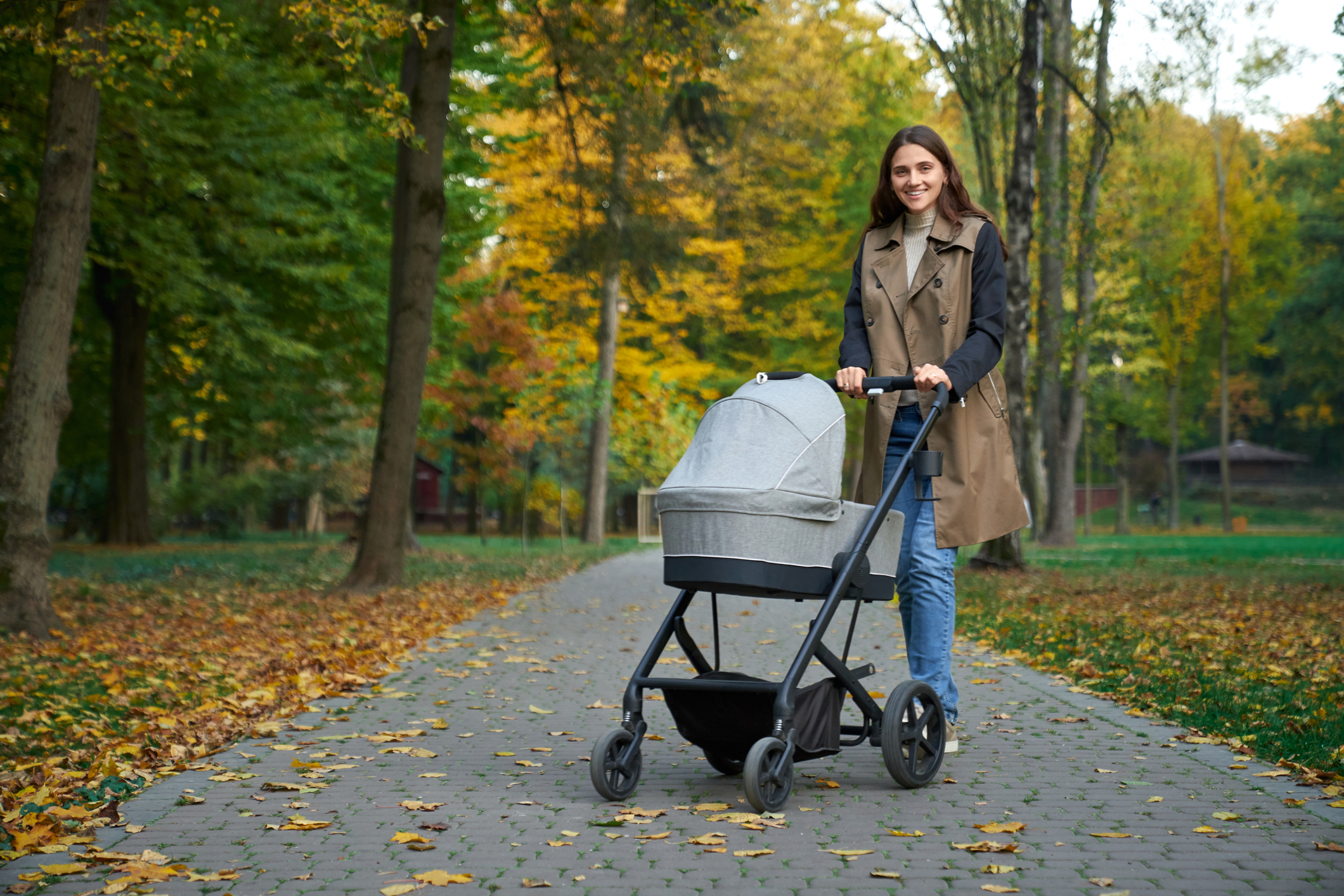 A parent walks their baby in a stroller with a bassinet attachment.