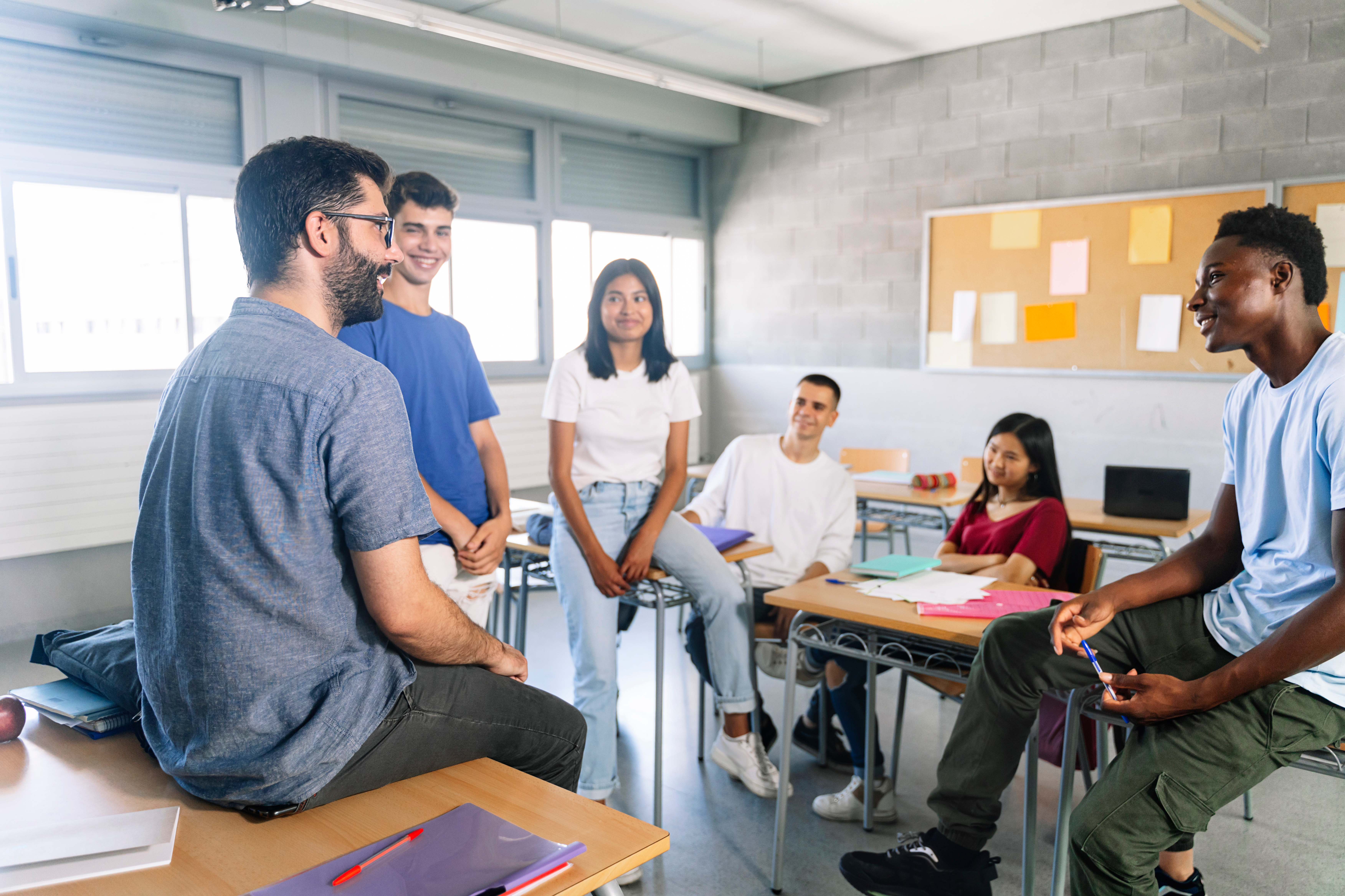 Étudiants adolescents écoutant et parlant avec un jeune enseignant sympathique - Discussion de groupe dans l'enseignement secondaire