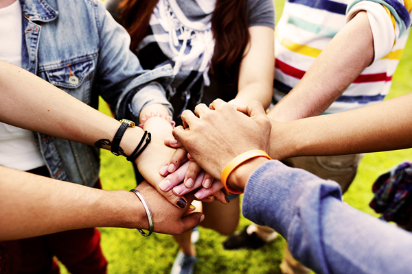 Group of six people with their hands stacked on top of each other showing togetherness