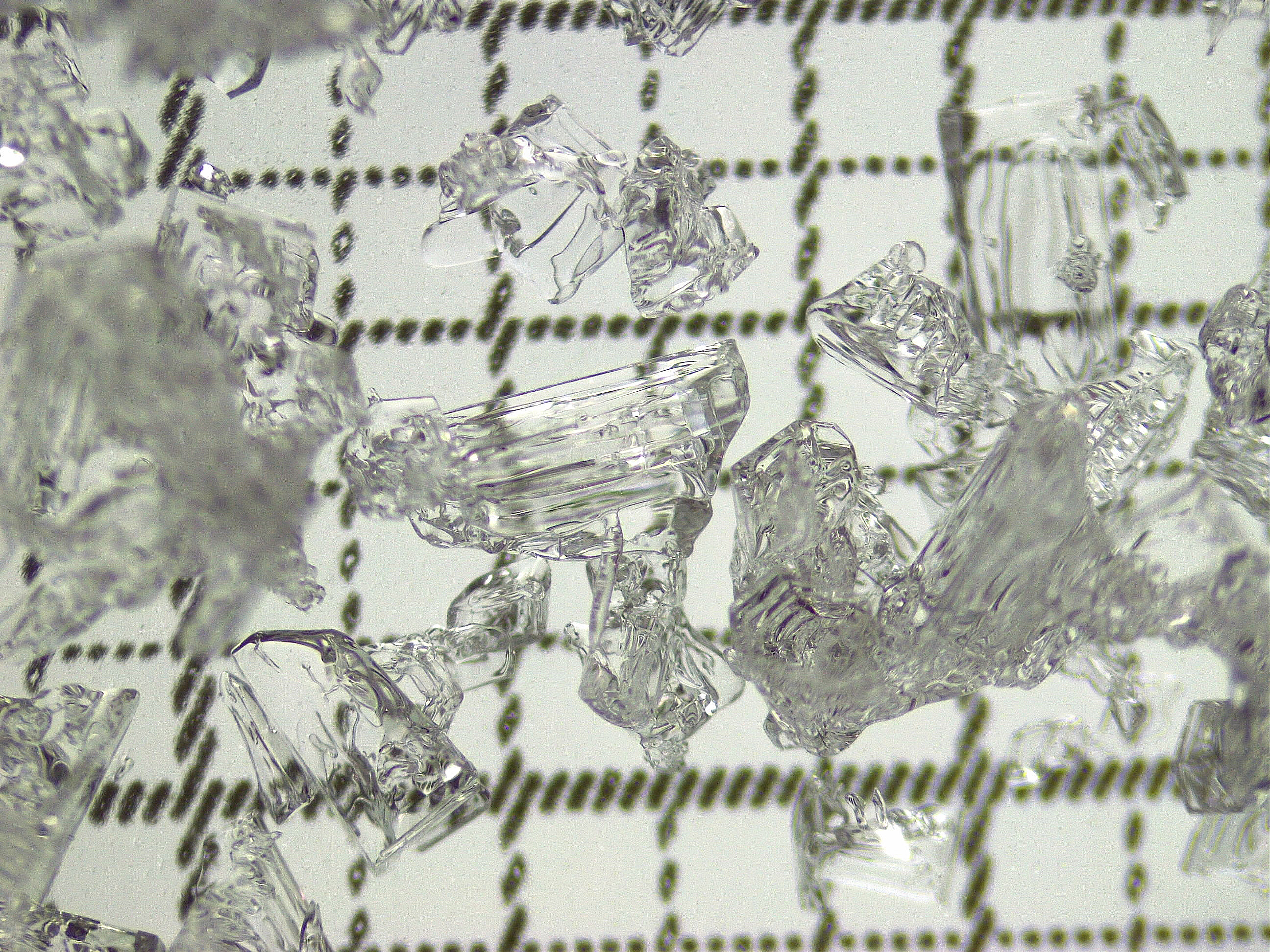 Microscopic pieces of ice crystals on a background of grid lines.