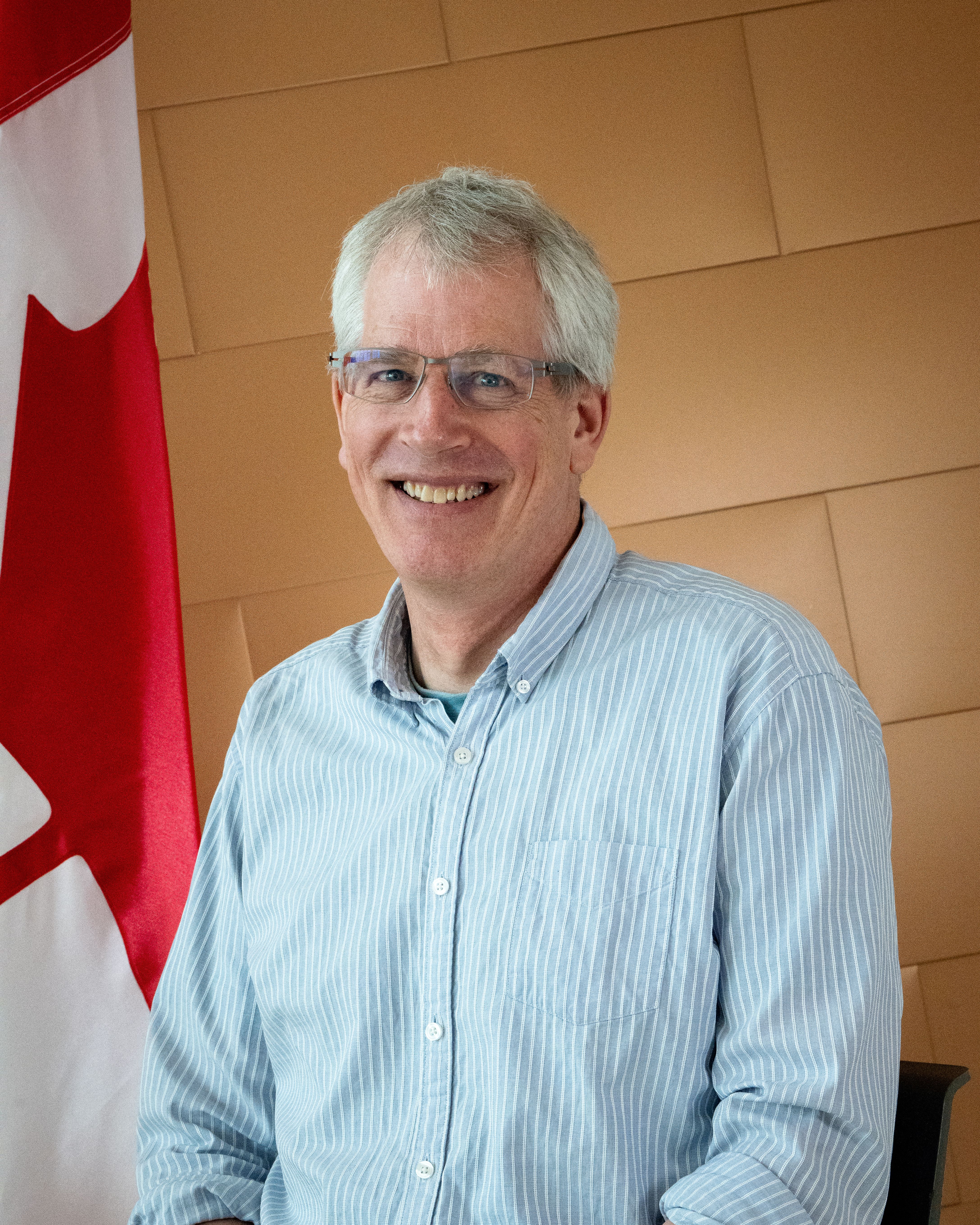 Headshot photo of man with glasses smiling.
