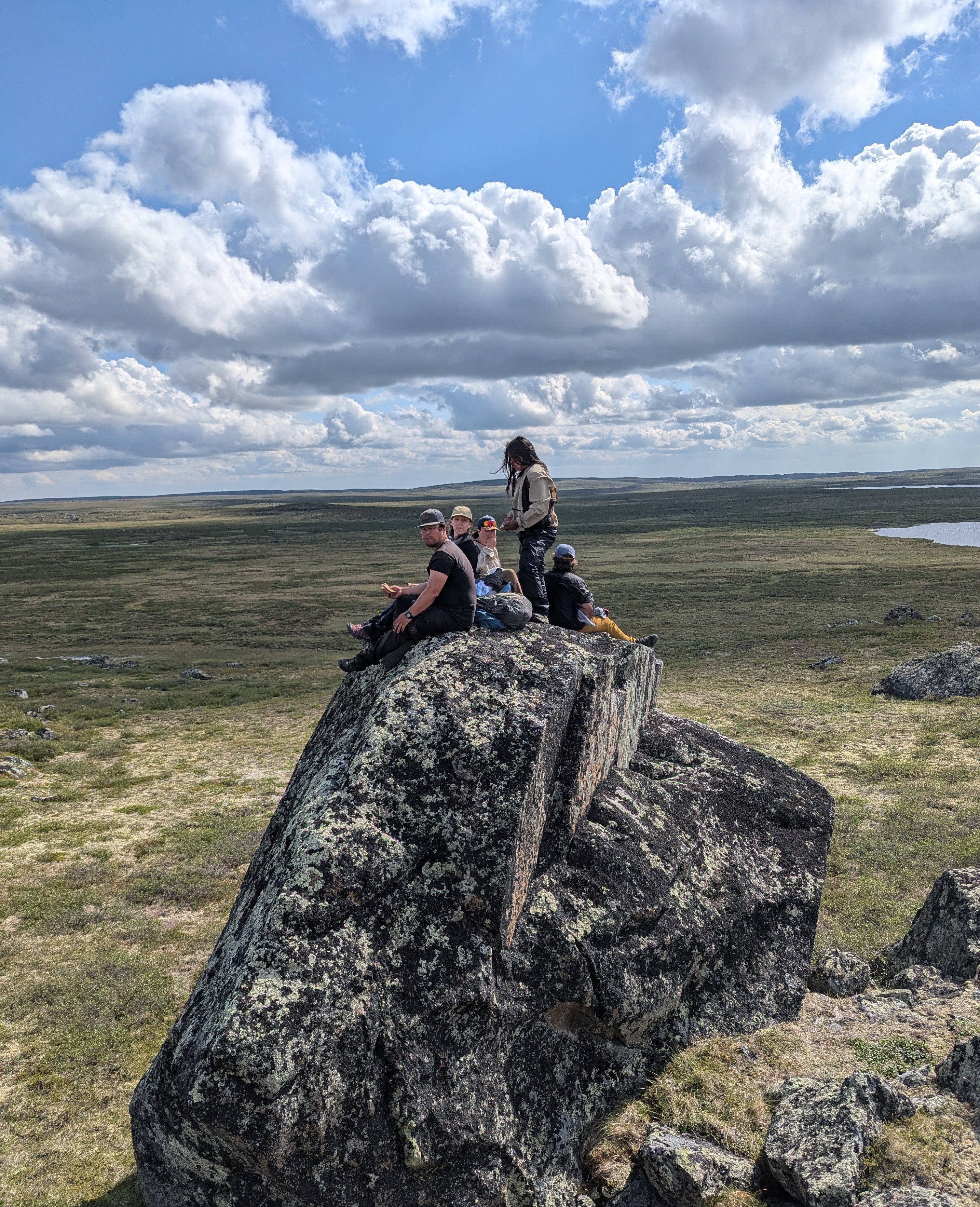 Five young people sit on top of a huge rock.