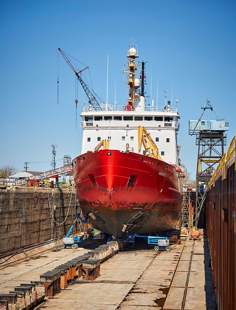 Red hull of Canadian Coast Guard Ship Admundsen on blocks in a dry dock