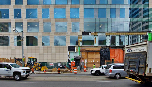 The front of a glazed building with vehicles passing by