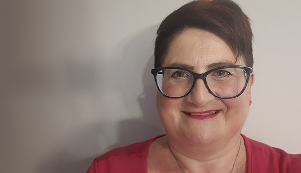 A smiling woman wearing glasses and a red shirt