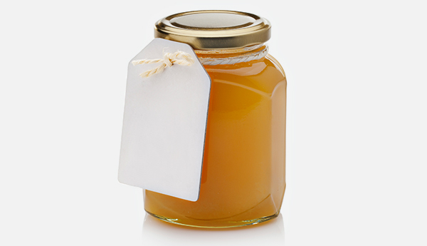 A small jar of honey with a paper tag attached