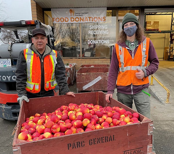 Une équipe avec une caisse de pommes.
