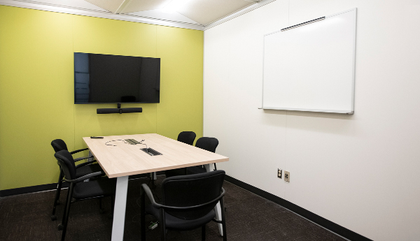 Salle de travail comprenant une table, des chaises, un tableau blanc et un écran