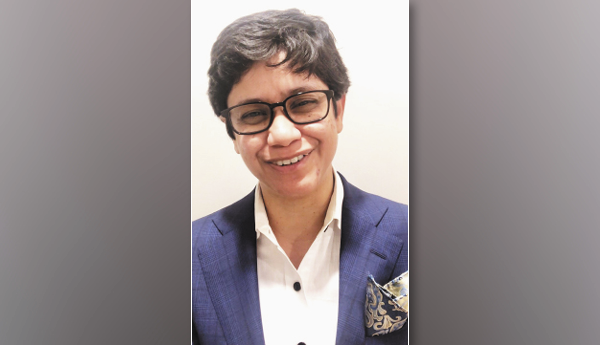 A close-up photo of a woman with glasses and short hair and wearing a suit.