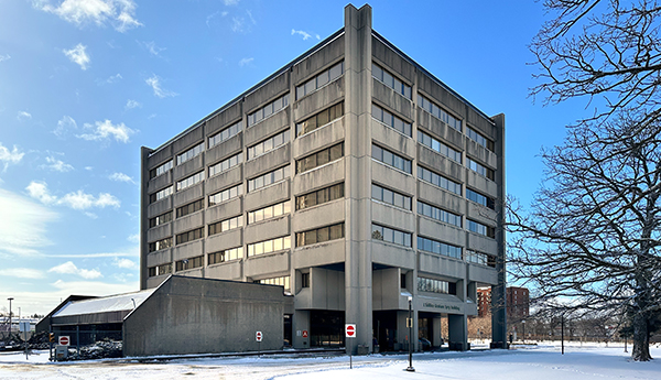 The exterior of a short, concrete building surrounded by snow.