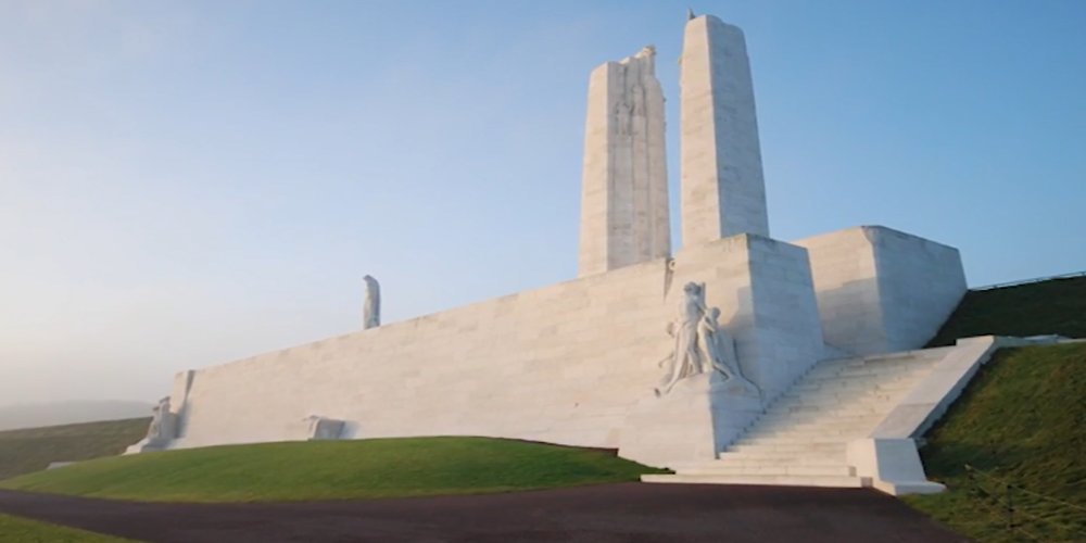 A large white stone monument with 2 large pillars and a green lawn in the front.