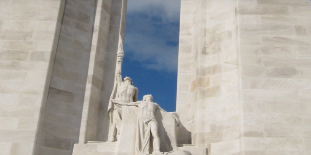 A carving of 2 anguished figures between 2 white stone pillars.