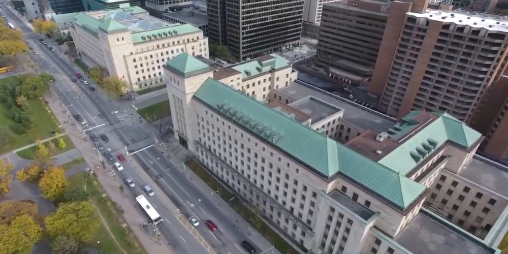 An aerial photo of 2 large government buildings with green roofs.