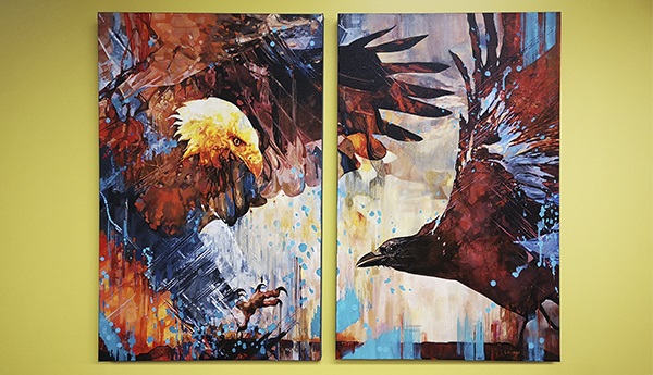 2 paintings side by side on a wall of an eagle and a crow in bright colours.