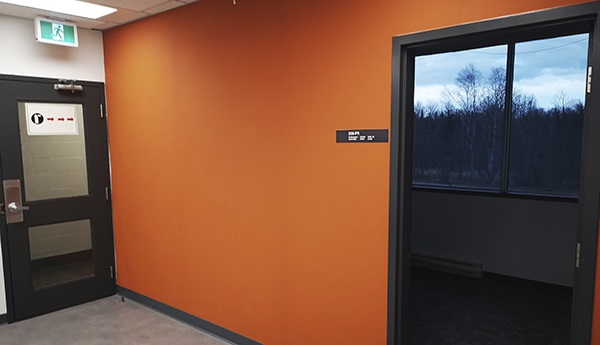 An orange wall with an open black door.
