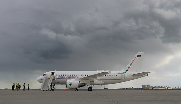 A white airplane on a tarmac under a cloudy sky, with people nearby.