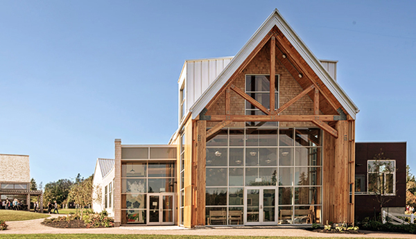 The front of a wooden barnlike structure with a triangular roof and many windows.
