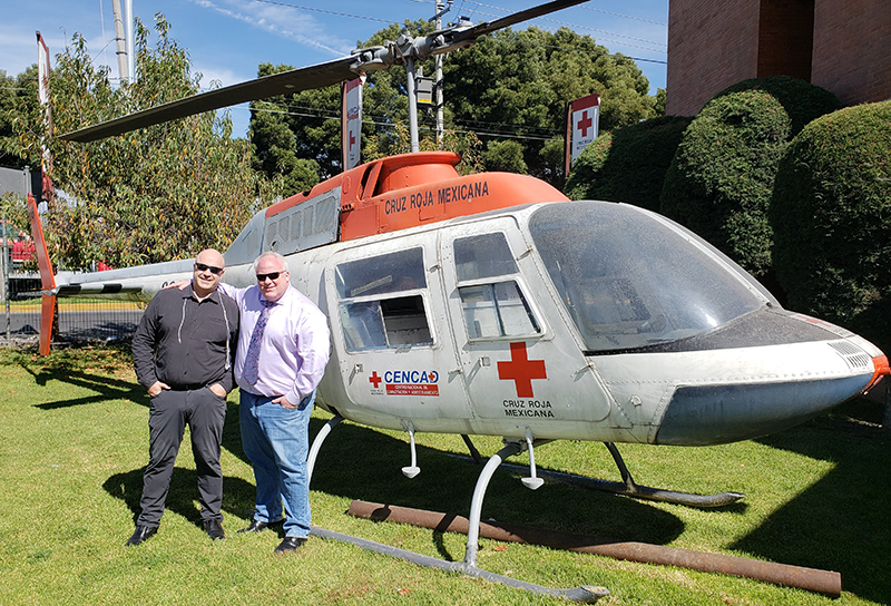 Two men standing by a helicopter with a large red cross on the front.