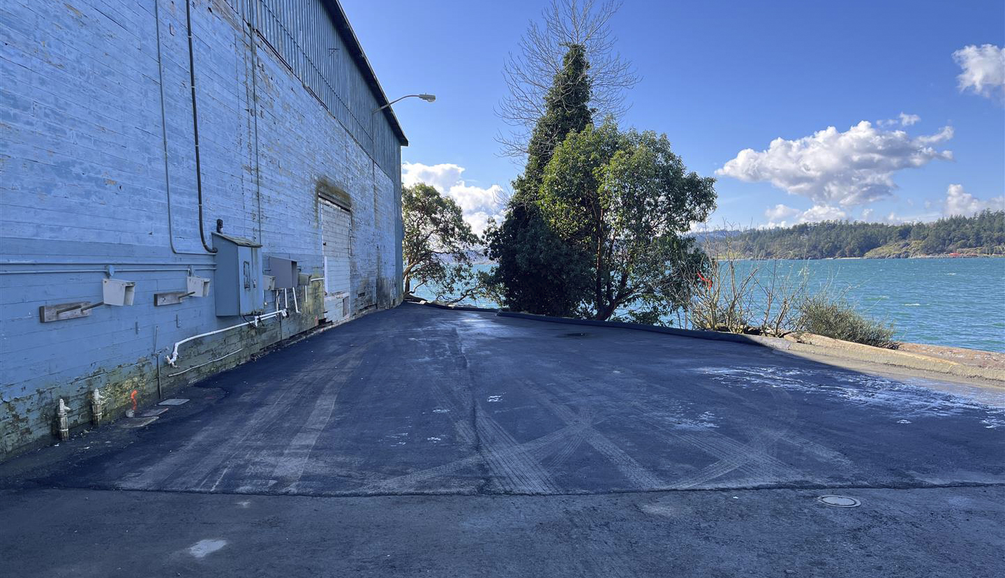 Un chemin fraîchement pavé entre un bâtiment et un rivage.