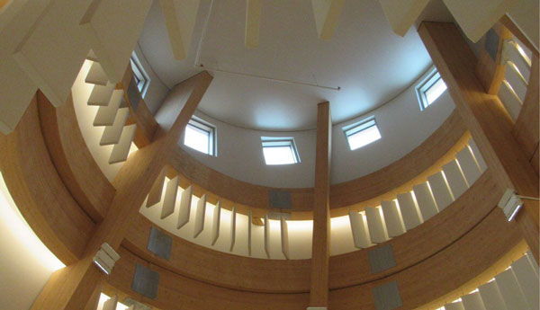 Low-angle view of the interior of a small dome with circular wooden panels and vertical rectangular white panels in different sizes