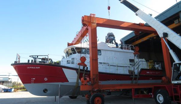 Une grue sort un bateau de sauvetage de l'atelier