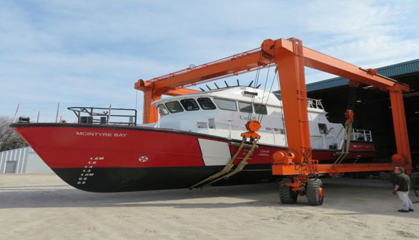 Une grue sort un bateau de sauvetage de l'atelier