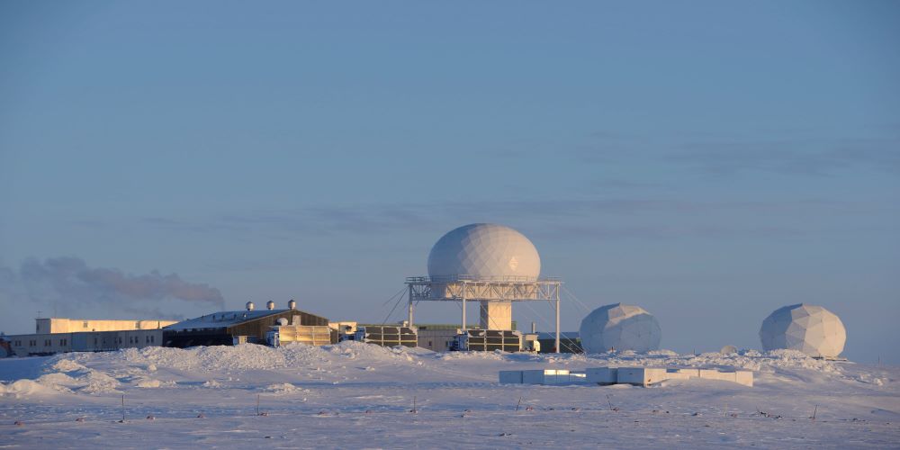 A snowy landscape with radar facilities in the background
