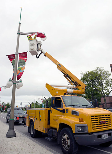 An employee in a bucket truck installing a Canada flag on a street light