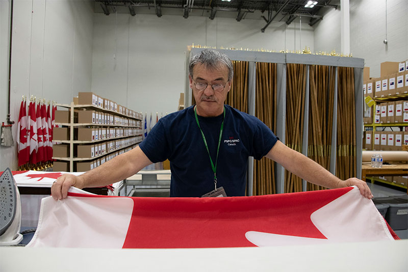 An employee folding a Canada flag