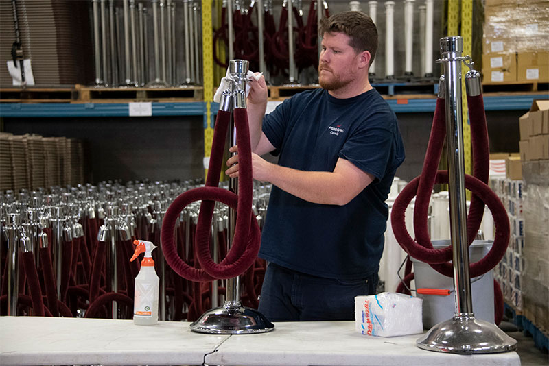 An employee cleaning a set of 2 red velvet stanchions