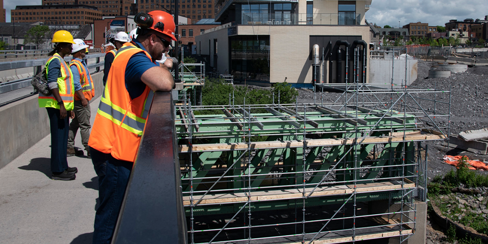 A group of people looking at a bridge structure under construction.