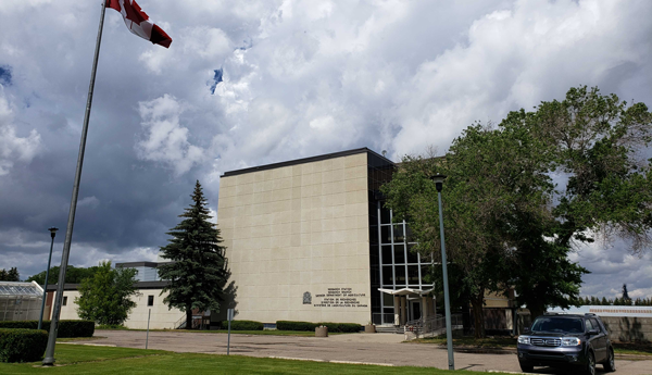 Building surrounded by trees and with Canadian flag out front.
