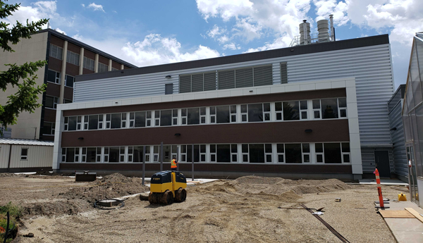 A machine performing landscaping work in front of a building.