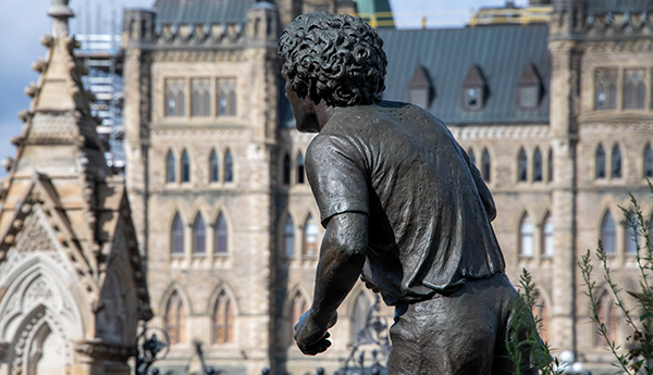 Back view of the Terry Fox bronze statue in front of an old building.