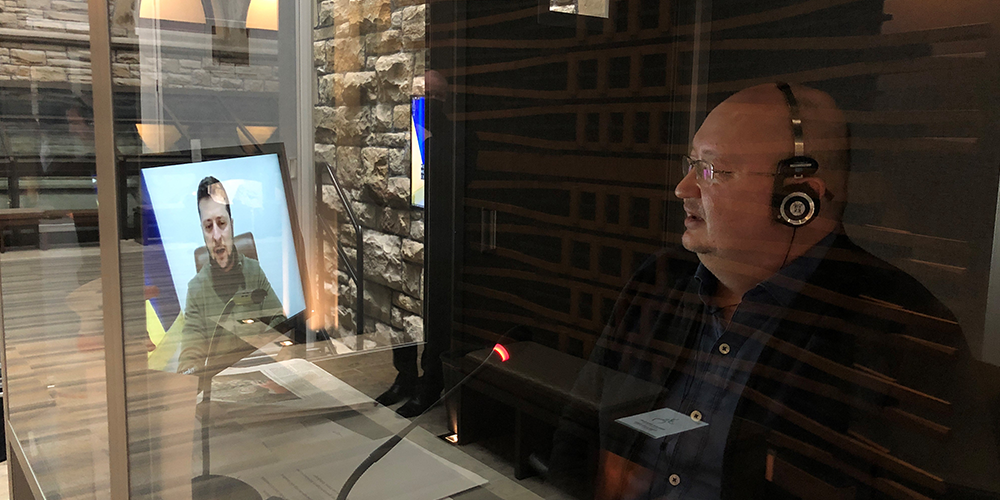 Petr Pogrebennyk, avec écouteurs, vu de côté assis dans un cubicule en verre regardant un écran d'ordinateur.