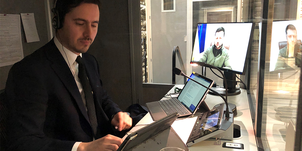 Anton-Emmanuel Demarchi, avec écouteurs, vu de face assis dans un cubicule en verre devant plusieurs écrans d'ordinateur.