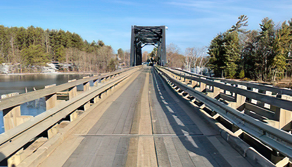 Perspective view of a single-lane structure made of new wood with a blue sky and trees in the background.