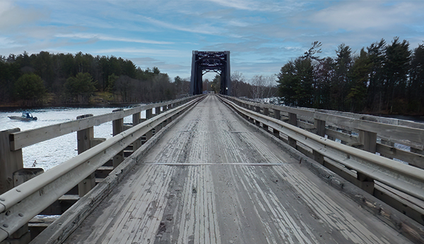 Grey photo of a perspective view of a single-lane structure made of old wood.