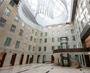Enlarged image of the curved staircase wrapping around a glass elevator leading to an upper-level walkway.