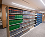 Enlarged image of the Library reading area with armchairs and tables, surrounded by legal reference collections, high-density shelving, and study spaces.