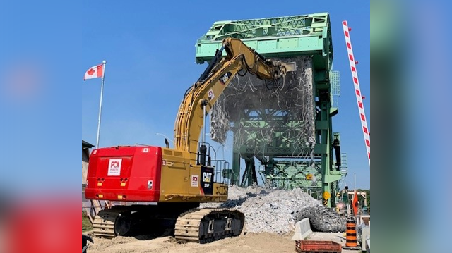 Excavator-mounted hydraulic hammer demolishing the concrete counterweight on the west approach of the Lasalle Causeway Bascule Bridge.